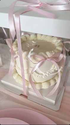 a white cake with pink ribbon in a box