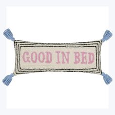 a pillow that says good in bed with tassels on the front and back