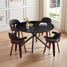 a table with four chairs around it in front of a window and flowers on the table