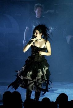 a woman in black dress on stage with microphone