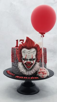 a cake with a clown face on it and a red balloon attached to the top