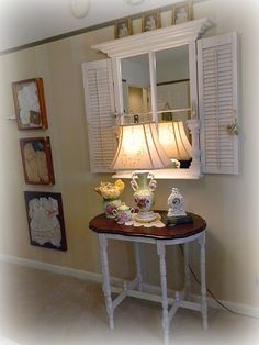 a table with some tea cups on it in front of a mirror and shutters