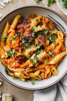 a bowl filled with pasta and sauce on top of a white cloth next to garlic