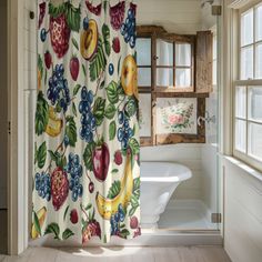 a bathroom with a shower curtain that has fruit printed on it, along with a bathtub and window