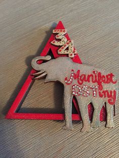 an elephant brooch sitting on top of a wooden table next to a red triangle