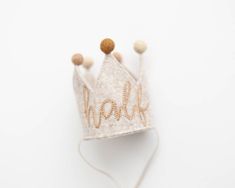 a white crown with gold lettering on it sitting on top of a table next to a string