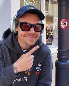 a man wearing headphones and pointing to the side with his finger on a pole