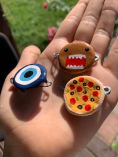 hand holding three different types of magnets in it's palm, one with an evil eye and the other with pizza on it