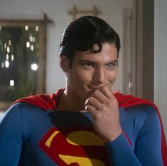 a man in a superman costume poses for the camera with his hand on his chin