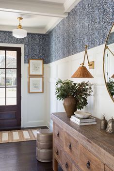 the entryway is decorated with blue wallpaper and wooden furniture, along with a potted plant