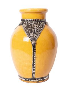 a yellow vase with an intricate design on the front and side, sitting against a white background