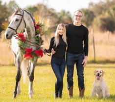 a man and woman are standing next to a horse with a wreath on its back