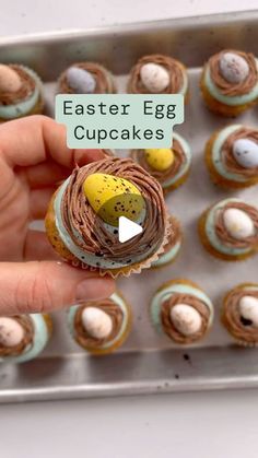 a person holding an egg cupcake with chocolate icing and mini eggs in it