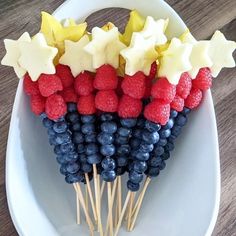 a white plate topped with red, white and blue fruit on skewered sticks