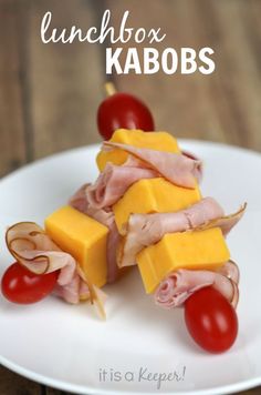 a white plate topped with ham and cheese on skewers next to cherry tomatoes