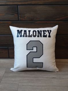 a pillow that has the number two on it and is sitting against a wooden wall