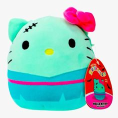 a hello kitty stuffed animal with a pink bow on its head and blue body, sitting next to a tag that says hello kitty