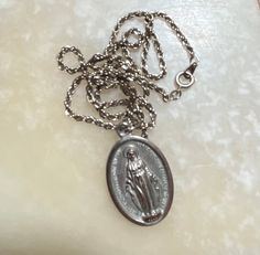 "This listing is for a silver-tone Miraculous medal. The oval pendant of Mary measures 1 1/4\" by 3/4\". The sturdy twisted chain measures about 17\". No silver markings on this necklace. Mary on one side, sacred heart on the other. The shipping weight will be 2 ounces." Vintage Silver Necklace With Miraculous Medal, Silver Miraculous Medal Necklace For Commemoration, Twisted Chain, Saints Medals, Miraculous Medal, Celtic Cross, Oval Pendant, White Tea, Blue Rhinestones