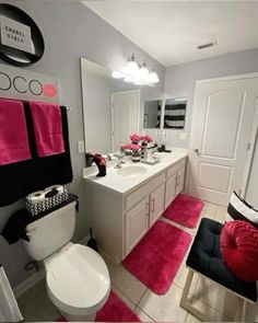 a white bathroom with pink rugs and black accents