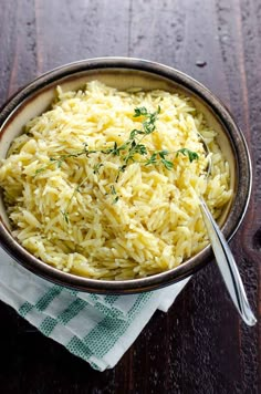 a bowl filled with rice sitting on top of a wooden table next to a fork