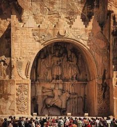 a group of people standing in front of a large stone structure with carvings on it