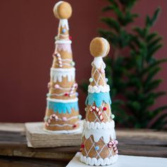 two gingerbread christmas trees sitting on top of a wooden table next to each other