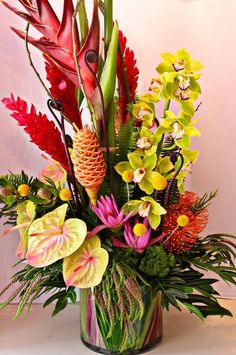 a vase filled with lots of different types of flowers and greenery on top of a table