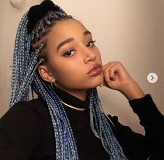 a woman with blue braids on her hair looking at the camera while wearing a black shirt