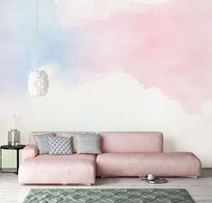 a pink couch sitting in front of a wall with a painting on it's side