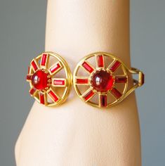 "This gorgeous bracelet features two large red glass cabochon stones surrounded by emerald cut red stones and set in gold-tone metal. This unusual bracelet has an art moderne look and dates to the 1940s. It has a spring hinge on the back that is in great working order. I don't see a maker's mark on this piece, but it is well-made. The interior width is 2-3/8\" and the setting at the front is 1.25\" tall. The interior circumference is 6.5\". This bracelet is in wonderful condition and looks strik Red Stones, Spring Hinge, Gorgeous Bracelet, Maker's Mark, Gorgeous Art, Red Stone, Silver Cuff Bracelet, Vintage Rhinestone, Red Glass