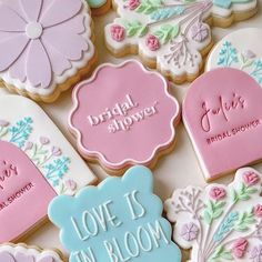 decorated cookies with wedding sayings are displayed on a white tableclothed surface in front of the words, bridal shower, love is in bloom