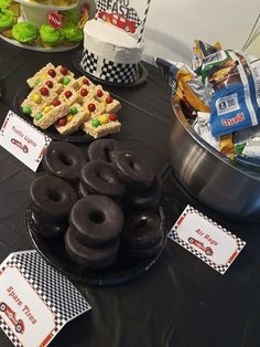 a table topped with lots of donuts and desserts on top of black cloth covered tables