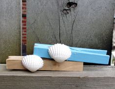 two seashells are sitting on top of a piece of blue and white wood