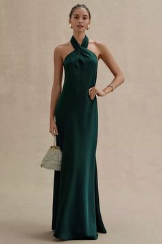 a woman in a long green dress standing with her hands on her hips