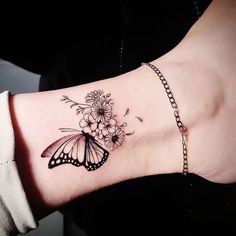 a woman's arm with a butterfly and flowers tattoo on the left side of her wrist