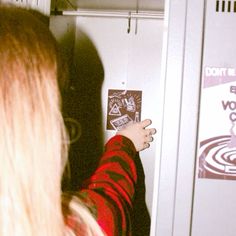 a woman is pointing at the door of a refrigerator that has stickers on it