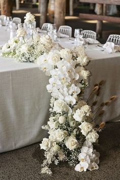 the table is set with white flowers and place settings for guests to sit down at