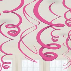 pink streamers hanging from the ceiling in a room with white walls and large windows