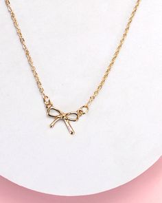 Adorn your neckline with the timeless charm of this mini gold bow charm necklace. The dainty bow pendant, crafted in radiant gold, brings an element of delicate elegance to your everyday style. Product Details: - Length: 16" with 3" extender - Charm: .5" x .35" - Anti-tarnish with double E-coating Minimalist Gold Jewelry With Bow, Dainty Gold Jewelry With Bow Detail, Dainty Adjustable Necklaces With Bow, Dainty Adjustable Necklace With Bow, Gold Dainty Bow Jewelry, Gold Necklaces With Bow Detail, Dainty Adjustable Bow Necklace, Bow Pendant, Mini Gold