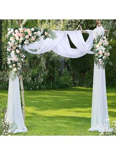 an outdoor wedding ceremony with white draping and flowers on the arch, along with greenery