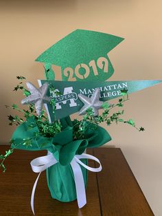 a green vase filled with flowers on top of a wooden table next to a sign