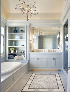 a large bathroom with blue cabinets and white bathtub, chandelier and sink