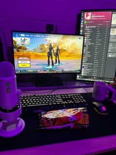 a computer desk with two monitors and a game controller on it, next to a cup of coffee