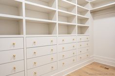 an empty room with many white drawers and gold knobs on the doors is pictured in this image