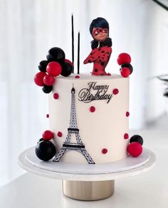 a birthday cake decorated with the eiffel tower and ladybug figurines