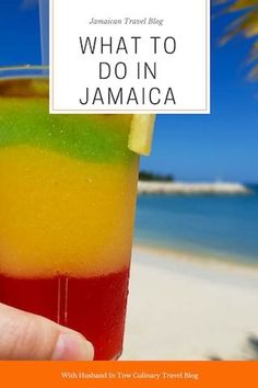 a person holding up a drink with the title what to do in jamaica on it