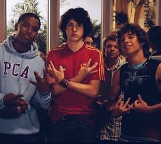 four young men standing in front of a window with their hands up to the side