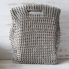 a silver purse sitting on top of a wooden table next to a white wall and floor