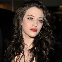 a woman with long hair wearing a black dress and posing for the camera at an event