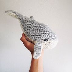 a hand holding a crocheted hat in the shape of a whale's head